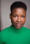 A photograph of Adura Onashile, a Black woman with cropped hair and a bright green top on