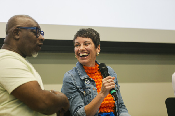 Kathryn Welch, a white woman with short brown hair, laughs and holds a microphone